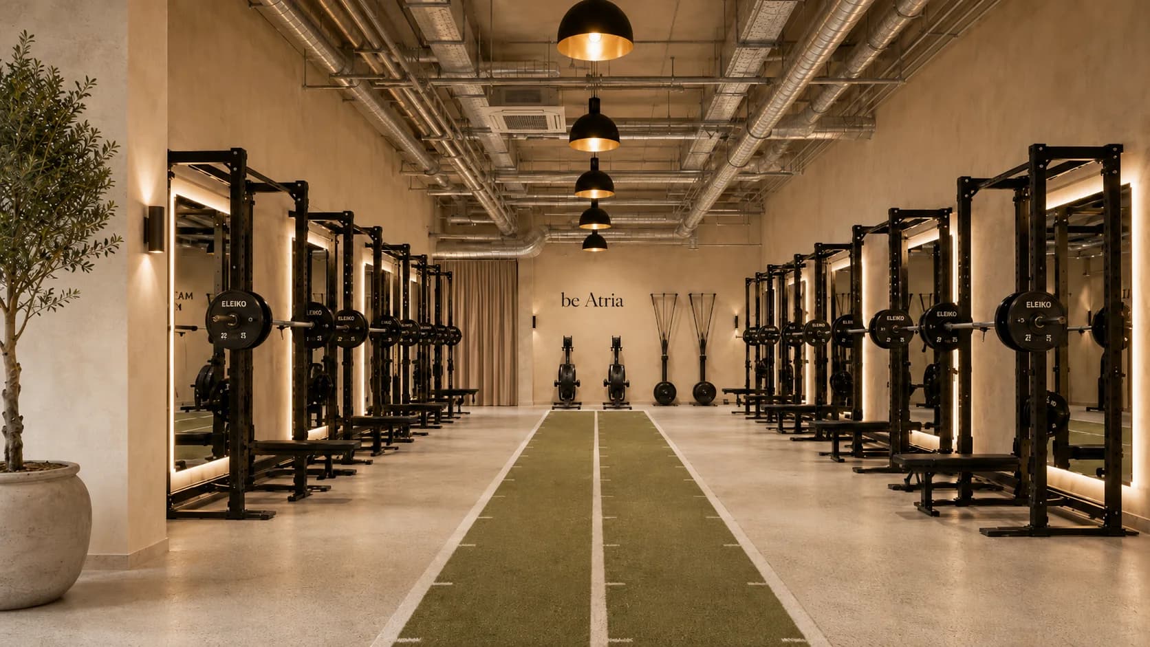 The be.Atria training floor: racks and turf lanes in warm plaster light